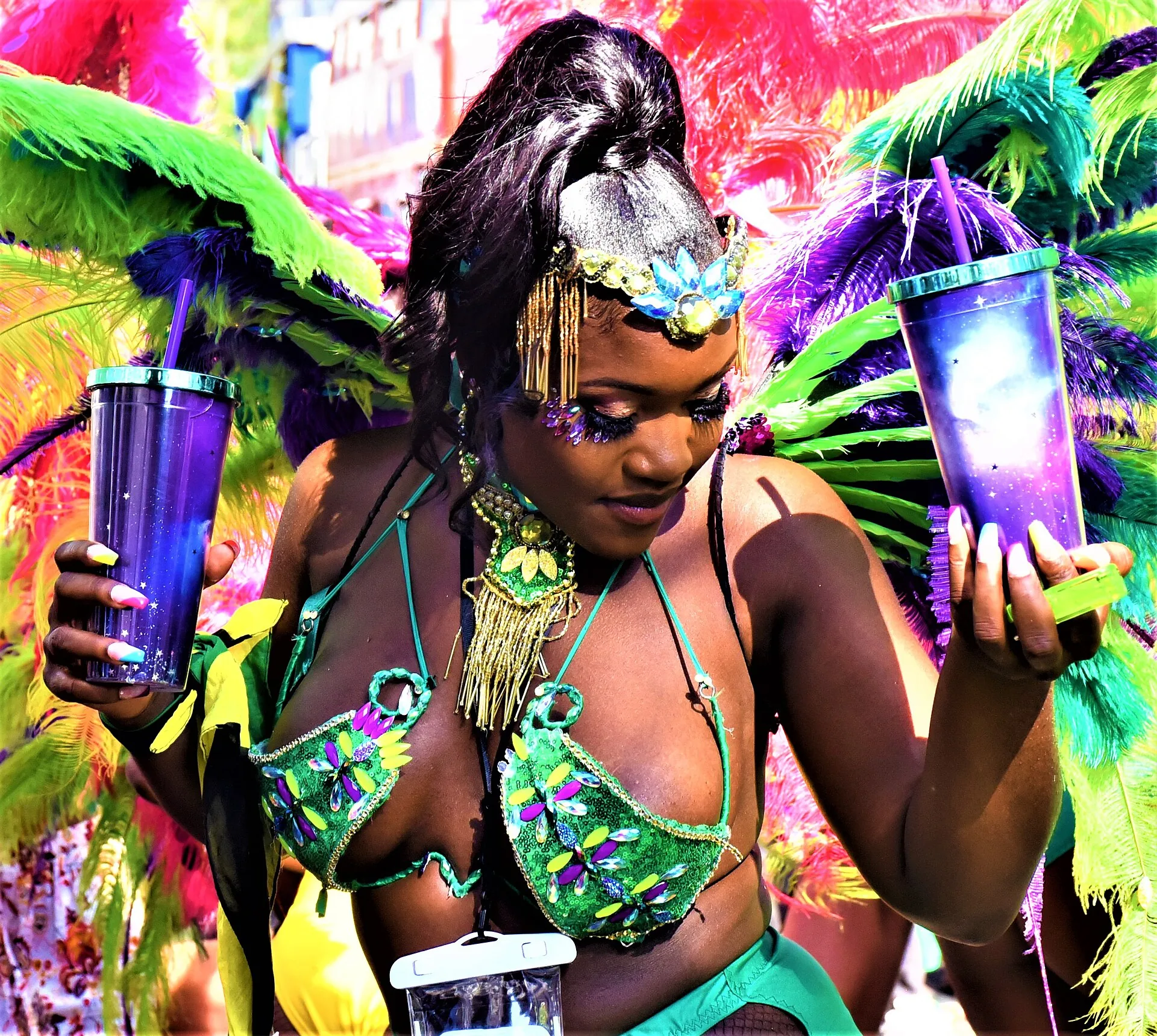 A Black masquerader dancing on the road at Notting Hill Carnival in a green and purple costume