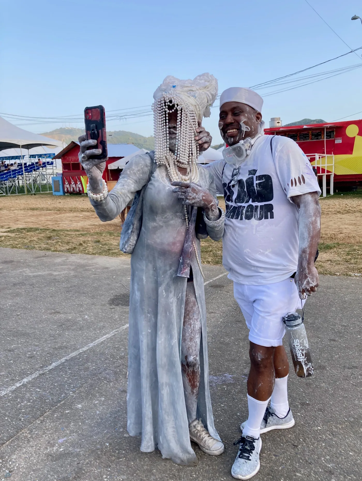 Two powder-covered masqueraders taking a selfie at Trinidad J’ouvert