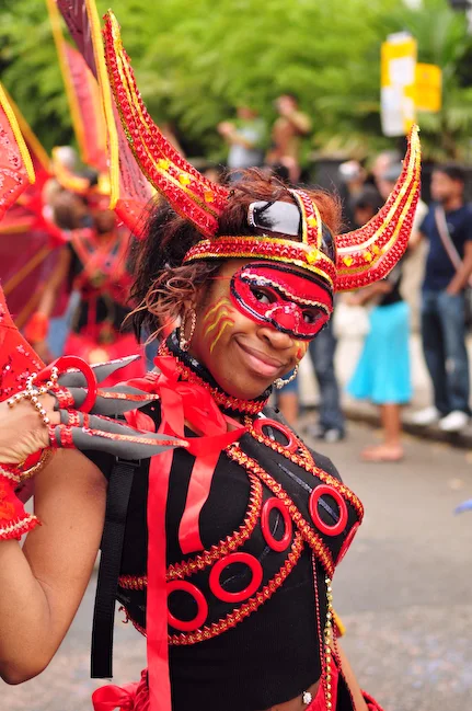 A Black female masquerader in a red and black horned devil costume at Notting Hill Carnival