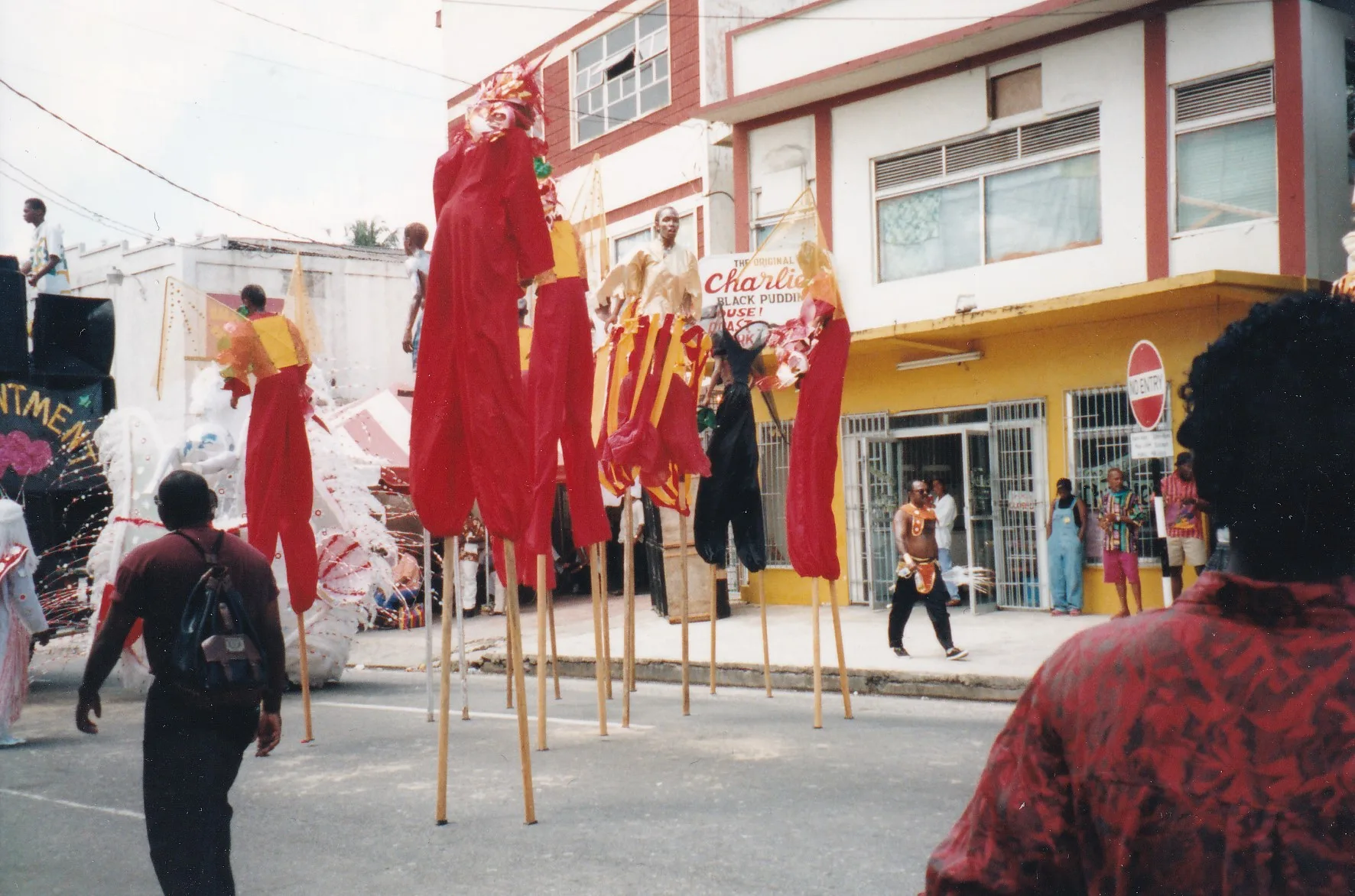 A line of Moko Jumbie masqueraders walking on stilts in Trinidad