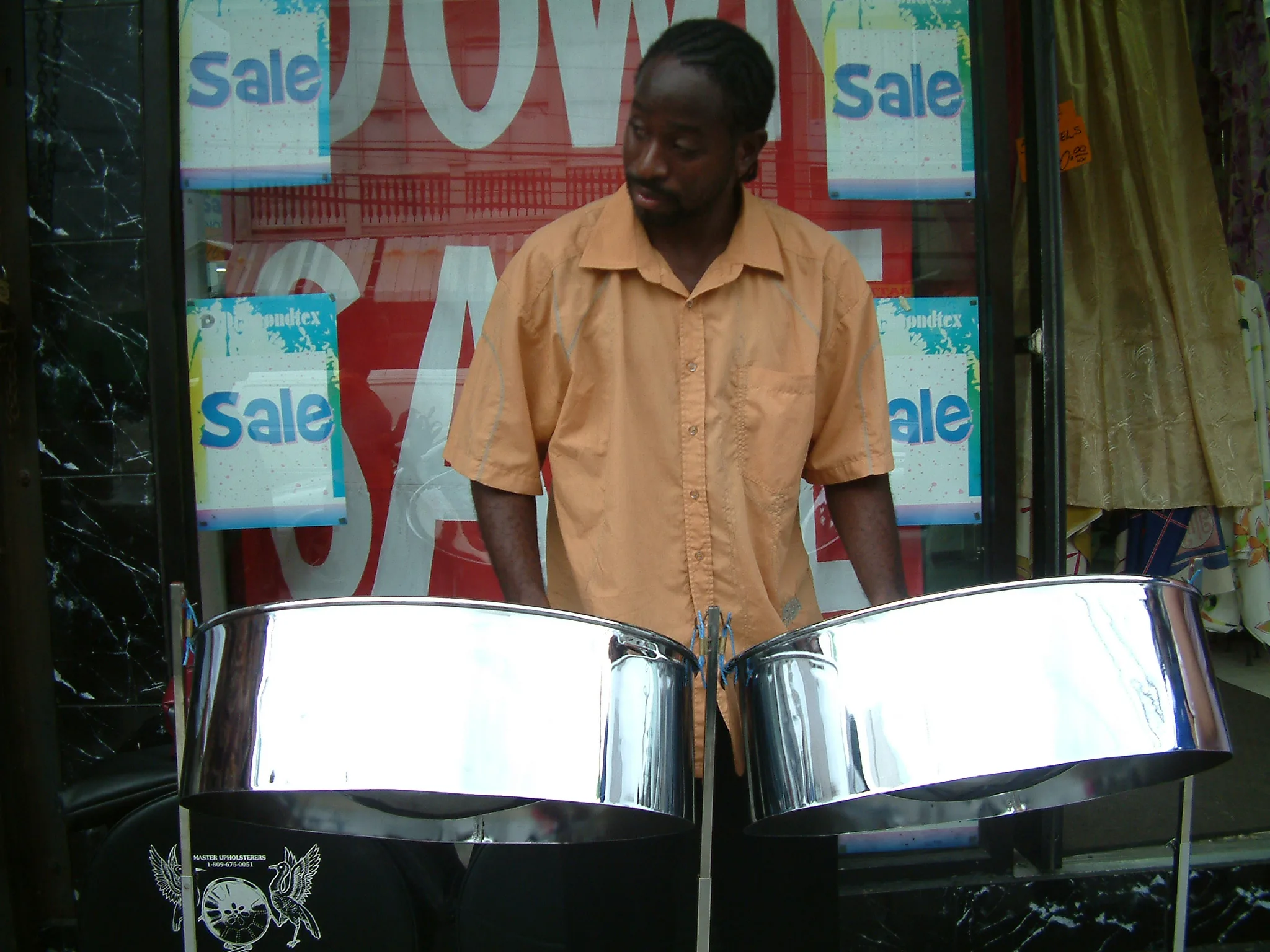 A pannist plays two steelpans on a street in Trinidad and Tobago