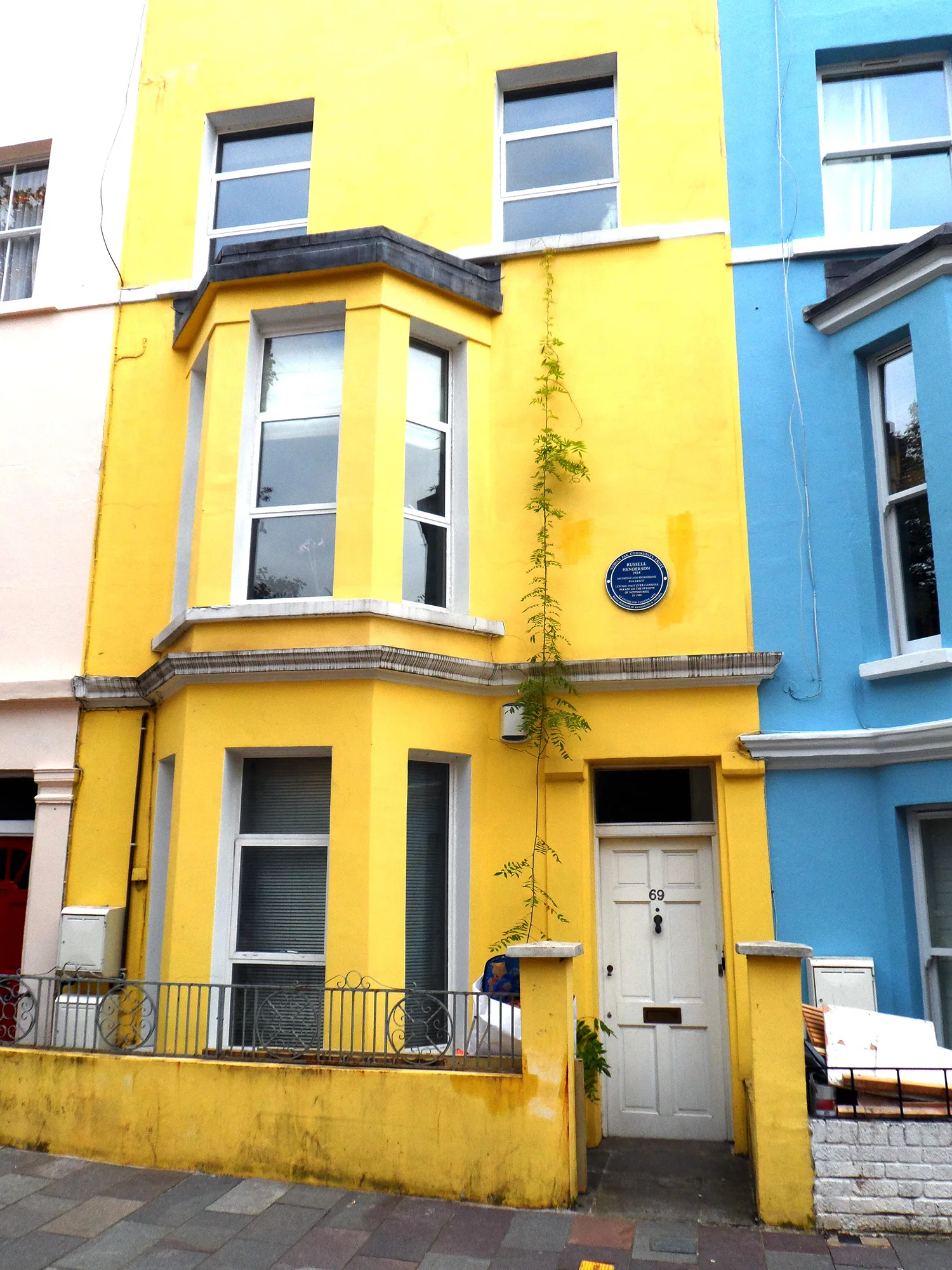 The yellow house at 69 Tavistock Road with a blue plaque honouring Russell Henderson