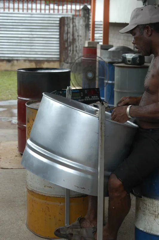 A steelpan tuner in Trinidad works on a pan using an electronic strobe tuner